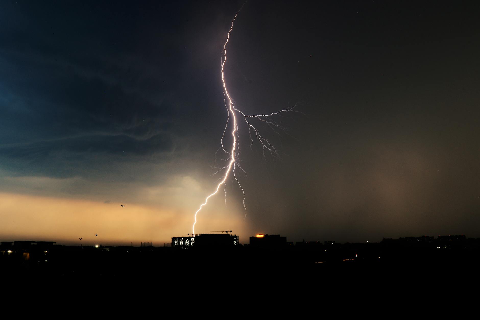 Lightning bolt striking over a city skyline during a severe storm