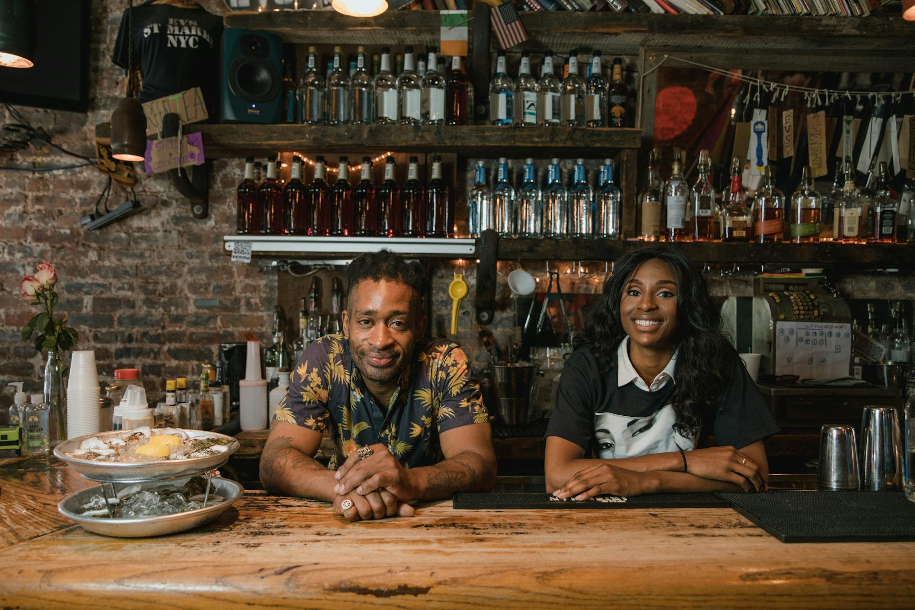 Bartenders serving drinks at a lively bar counter in Royal Oak