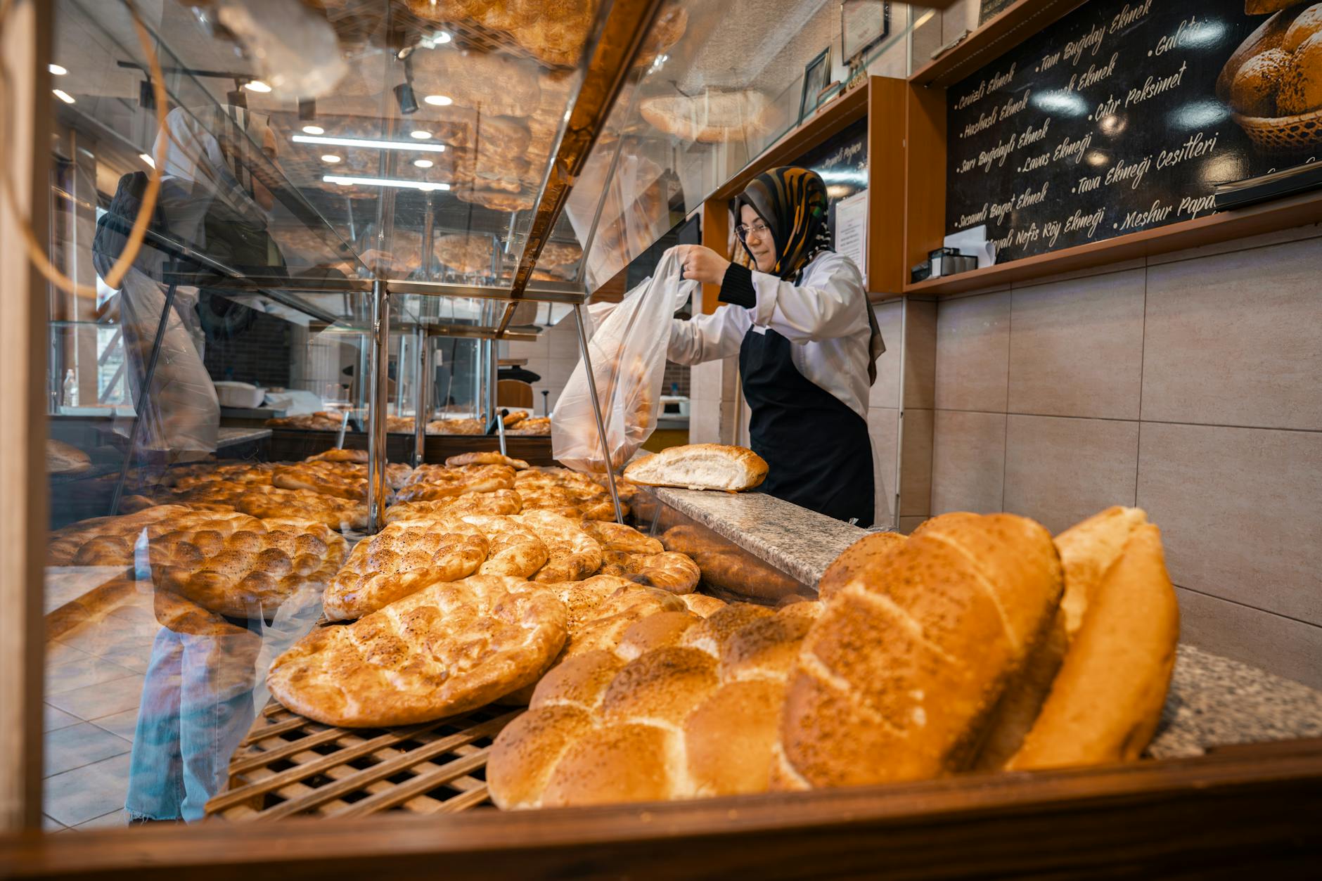 Baker packaging fresh golden-brown bread in a bakery